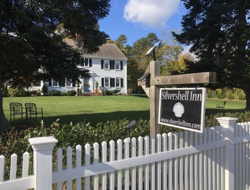 una cerca blanca con un cartel delante de una casa en Silvershell Inn, en Marion