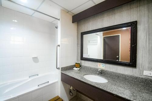 a bathroom with a sink and a tub and a mirror at Piman Garden Boutique Hotel in Khon Kaen