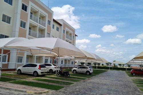 a group of cars parked next to a building with umbrellas at Cariri Vivenda - Apto completo com 02 quartos climatizados, estacionamento e portaria 24 horas in Juazeiro do Norte