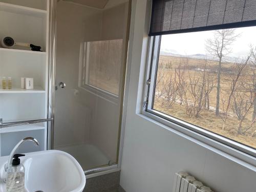 baño con ducha, lavabo y ventana en Bakkaflöt Guesthouse, en Varmahlid