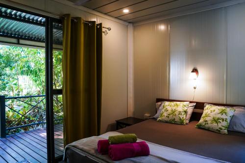 a bedroom with a bed and a window with a balcony at House in the palm forest in Carrillo