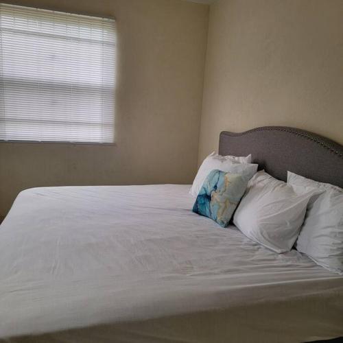 1 cama con sábanas y almohadas blancas y ventana en The Luxe Room & Suite, en Saint Michael