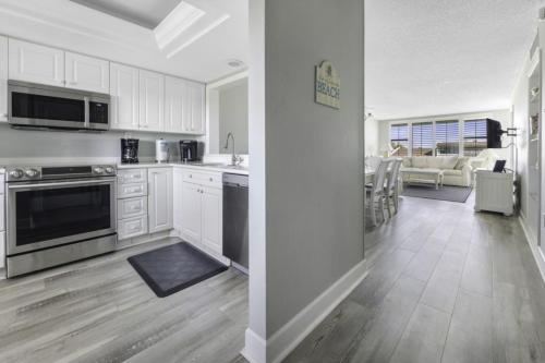 a kitchen with white cabinets and a living room at Loggerhead 314 condo in Sanibel