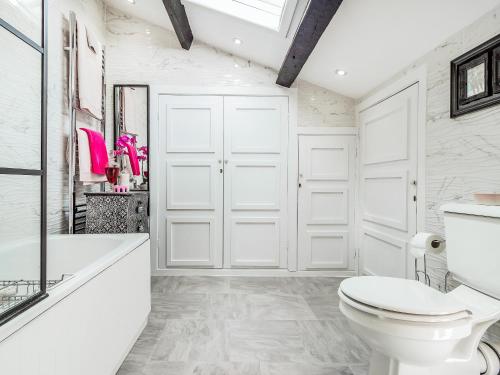 a white bathroom with a toilet and a bath tub at Llwynhelig House - Uk46395 in Cowbridge