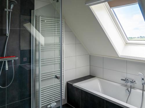 ein Badezimmer mit einer Badewanne und einem Dachfenster in der Unterkunft 20-person group home in the heart of Friesland in Leons