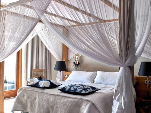een slaapkamer met een hemelbed en witte gordijnen bij Beautiful villa for 12 people in San Jose de sa Talaia