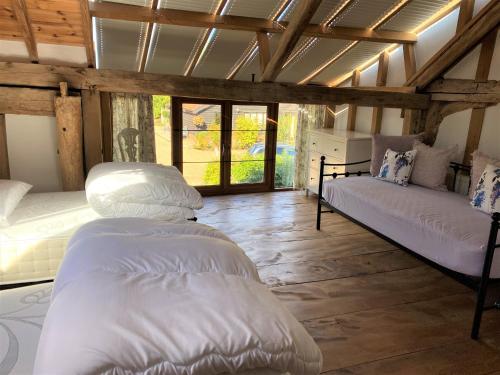 two beds in a room with wooden ceilings and windows at Brundish Suffolk Large 4-Bed Barn Stunning! in Woodbridge