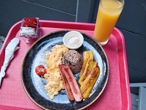 a plate of food on a pink tray with a drink at Arenal Memories. in Fortuna