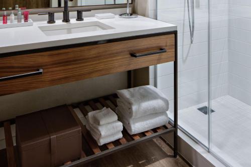 a bathroom with a sink and a pile of towels at Houston CityPlace Marriott at Springwoods Village in The Woodlands
