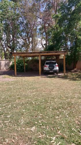 un coche aparcado bajo un pabellón de madera en un patio en Las Violetas en 