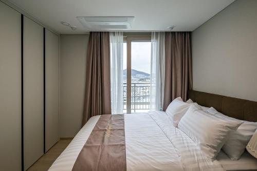 sypialnia z dużym łóżkiem i dużym oknem w obiekcie Ocean Terrace Yeosu w mieście Yeosu