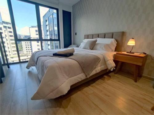 een slaapkamer met een groot bed en een groot raam bij BeKAWS: Suite in Quito