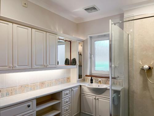 a white bathroom with a sink and a shower at The Byre in Tayvallich