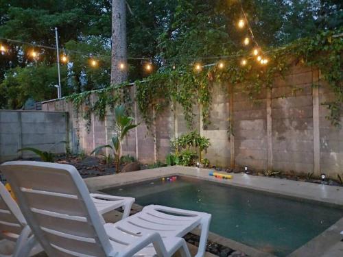 two chairs and a pool with lights and a fence at Uvita Stone House in Uvita