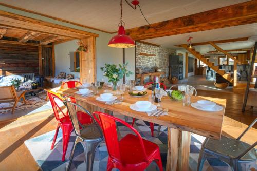 a dining room with a large wooden table and red chairs at La Ferme des Artistes - OVO Network in Mieussy