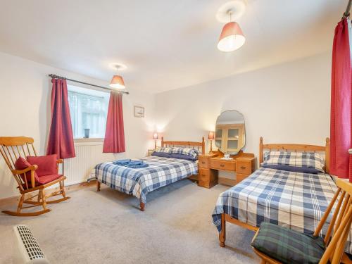 um quarto com 2 camas, uma secretária e uma cadeira em Brondeg Lodge em Crarae