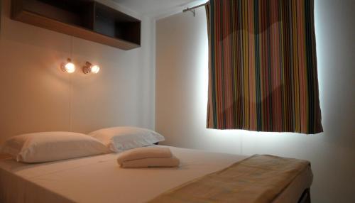 a bedroom with a bed with two pillows and a window at Camping Principina in Principina a Mare