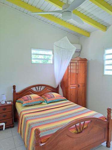 ein Schlafzimmer mit einem Holzbett und einer Holzkommode in der Unterkunft Gîte 2 à 4 personnes à la campagne in Le Moule