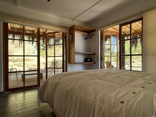 ein Schlafzimmer mit einem Bett in einem Zimmer mit Fenstern in der Unterkunft Casa Canoa in Canoas