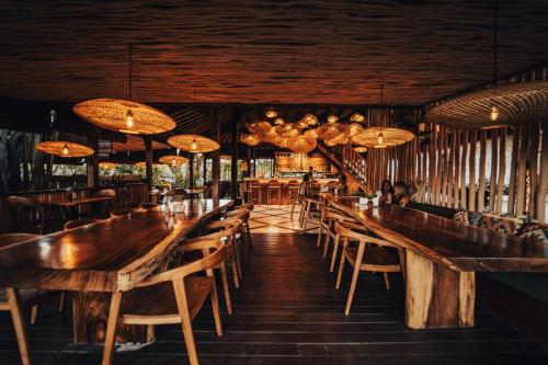 a restaurant with wooden tables and chairs and chandeliers at Kayu Mama Resort and Spa in Uluwatu
