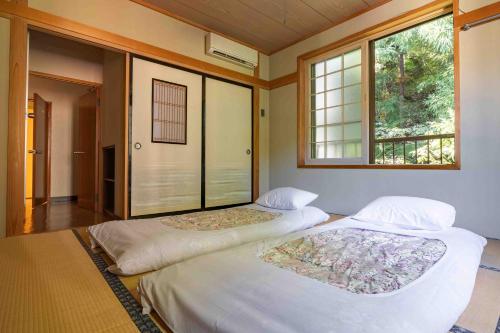 two beds in a room with two windows at Yamane in Nozawa Onsen