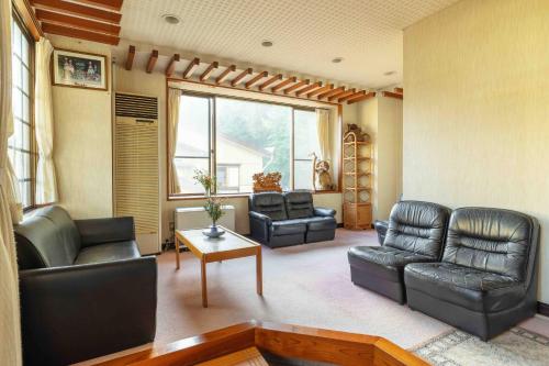 a living room with black leather furniture and a window at Yamane in Nozawa Onsen