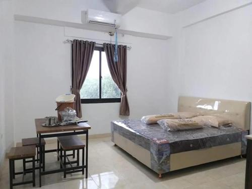 a bedroom with a bed and a table and a window at Puri Kanata in Pampang