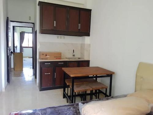 a kitchen with wooden cabinets and a table and a bed at Puri Kanata in Pampang