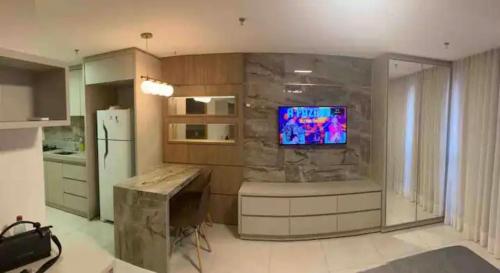 cocina con TV en una pared de piedra en Inova Flat completo no Condominio Cosmopolitan, en Palmas