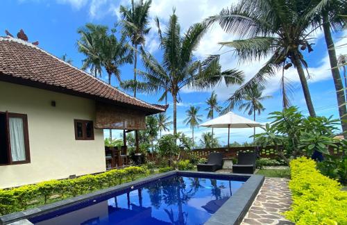 a villa with a swimming pool and palm trees at Lafyu Bali in Singaraja