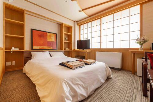 a bedroom with a large white bed and a tv at Nozawa View Hotel Shimataya in Nozawa Onsen