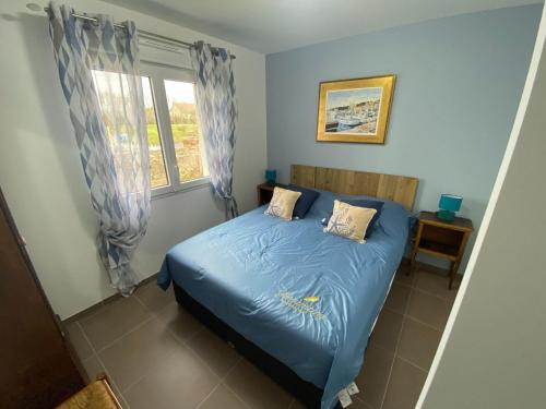 a bedroom with a bed with blue sheets and a window at Pretty holiday home in Cotentin in Gouville-sur-Mer