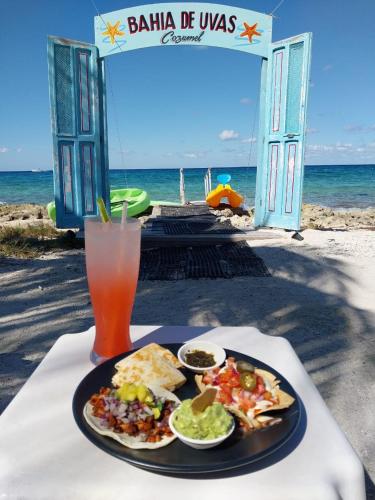 a table with a plate of food and a drink at Bahía uvas Bungalos in Banco Playa