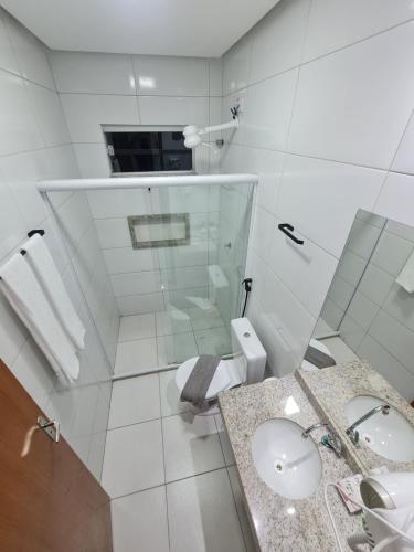 a white bathroom with a toilet and a sink at Bahia Trip Flats in Lençóis
