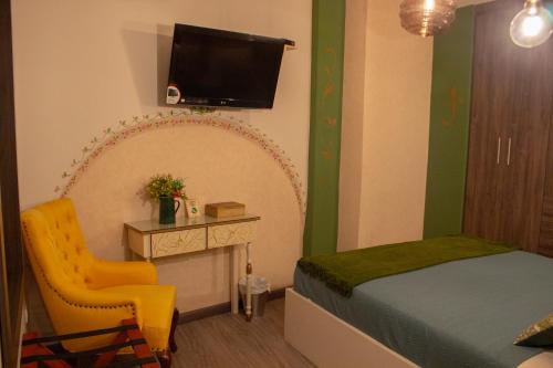 een slaapkamer met een bed en een stoel en een tv bij Ronda Hotel Boutique by Chat Noir in Cuenca