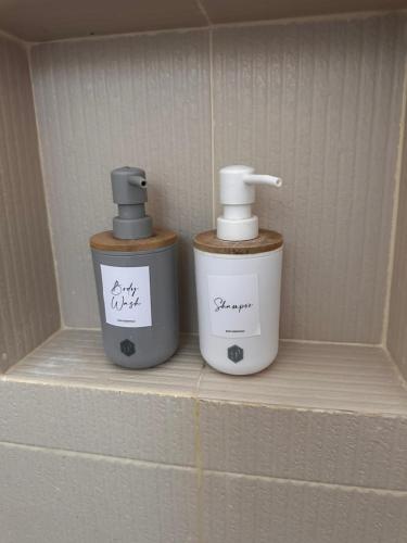 twee flessen odorizers op een plank in een badkamer bij CasaDel Beach House in Mabini