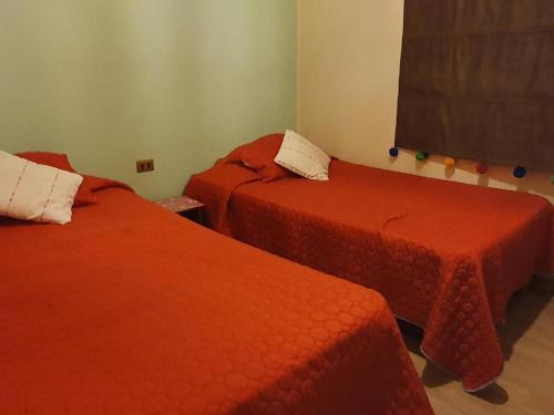 two beds in a room with red sheets at CABAÑA ENTRE ARRAYANES Y COPIHUES Selva VALDIVIANA in Valdivia