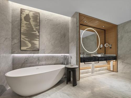 een badkamer met een wit bad en een wastafel bij Angsana Suzhou Shishan in Suzhou