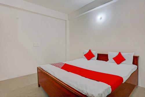 1 dormitorio con 1 cama con almohadas rojas y blancas en OYO Flagship City Light Hotel, en Kānpur
