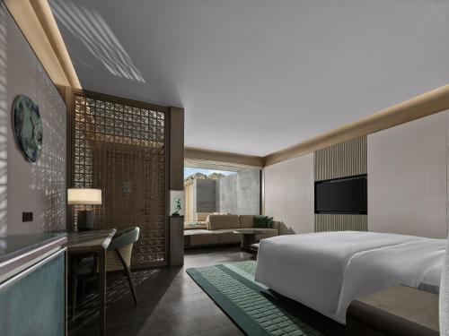 a bedroom with a bed and a living room at Banyan Tree Suzhou Shishan in Suzhou