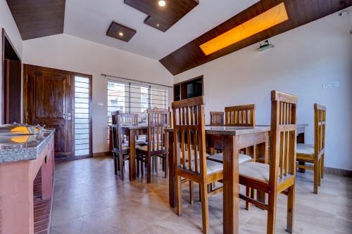 a kitchen and dining room with wooden tables and chairs at Super OYO Collection O 81054 G Silver Srj Thaneesh Residency in Ooty