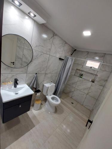 een badkamer met een toilet, een wastafel en een spiegel bij La casita de Fran in Comandante Luis Piedra Buena