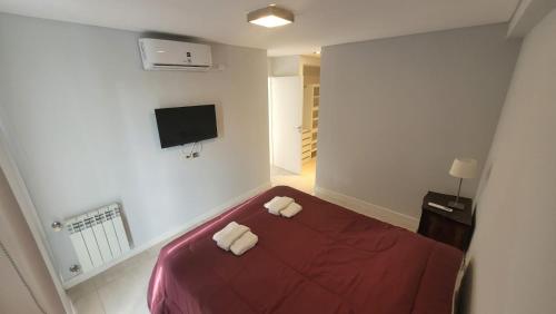 1 dormitorio con 1 cama roja y 2 toallas blancas en Dean funes suites 302 en Salta