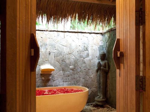a bathroom with a bath tub with a statue in it at Villa Mathis in Canggu