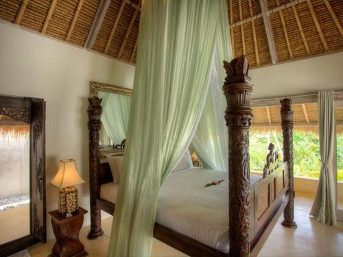 1 dormitorio con cama con dosel, cortinas y lámpara en Villa Mathis, en Canggu
