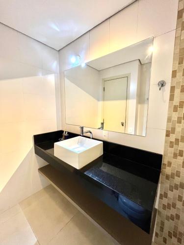 a bathroom with a sink and a mirror at Flat Premium -Acesso a pé ao shopping Center vale - Edifício Summit (Ar condicionado) in São José dos Campos