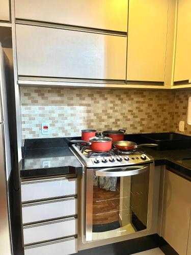 a kitchen with a stove with pots and pans on it at Flat Premium -Acesso a pé ao shopping Center vale - Edifício Summit (Ar condicionado) in São José dos Campos