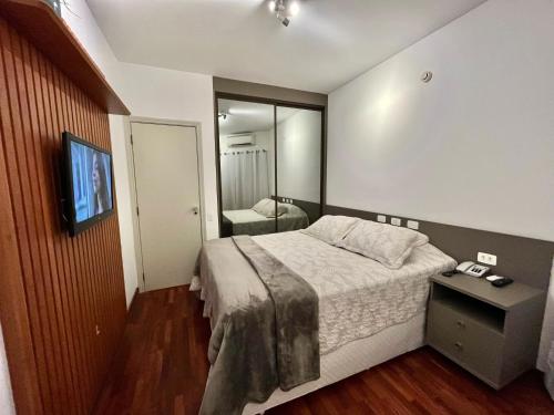 a bedroom with a large bed and a mirror at Flat Premium -Acesso a pé ao shopping Center vale - Edifício Summit (Ar condicionado) in São José dos Campos