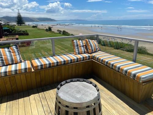 a balcony with a couch and a view of the beach at Ultimate Beach Front in Waimarama