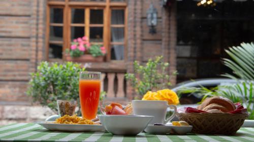 una mesa con un plato de comida y un vaso de zumo de naranja en Ronda Hotel Boutique by Chat Noir en Cuenca